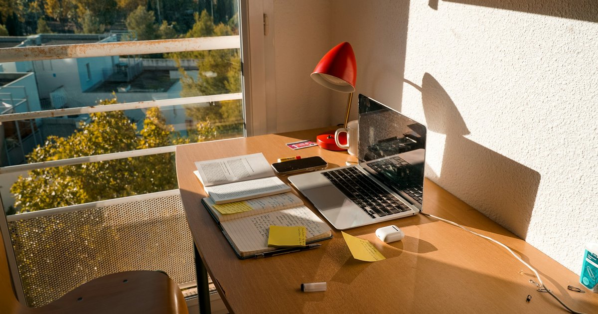 窓辺の机の上のノートPCとノート